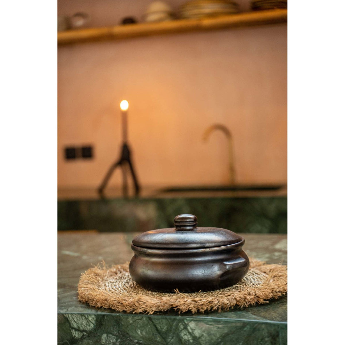Set de table en jonc de mer posé sur un plan en marbre vert sous une cocotte sombre