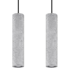 Deux tubes de la suspension Luvo en béton gris clair vus de près avec leurs câbles noirs et leurs ouvertures basses