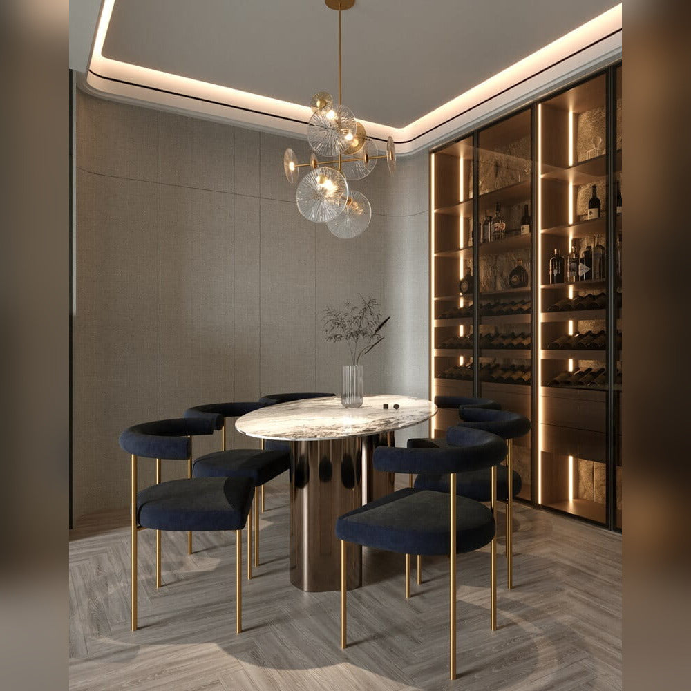 Suspension Allure allumée au-dessus d'une table ovale en marbre entourée de chaises bleu nuit à pieds dorés devant une cave à vin vitrée