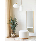 Suspension Argalo et un globe côtelé plus large au-dessus d'un pouf en tissu blanc près d'un miroir à cadre en bois