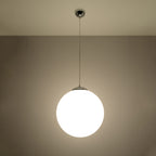 Suspension boule Ugo allumée qui diffuse une lumière douce à travers son verre blanc