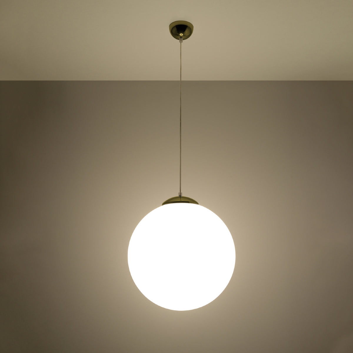 Suspension boule Ugo allumée qui diffuse une lumière douce à travers son verre blanc laiteux