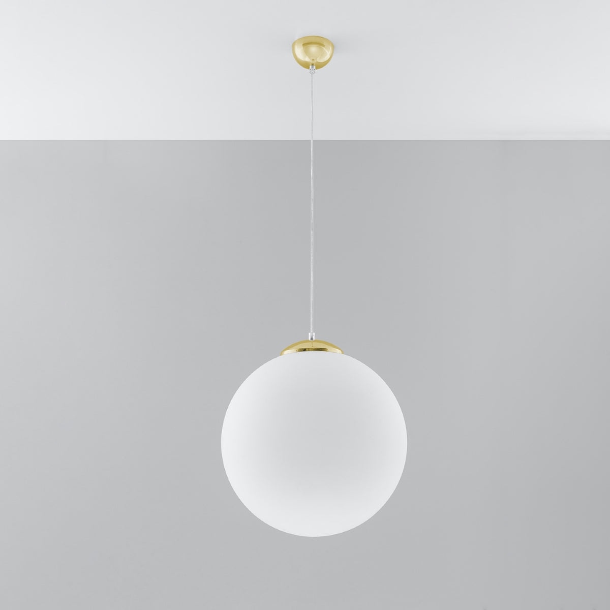 Suspension boule Ugo en verre blanc pendue sous un plafond blanc devant un mur gris