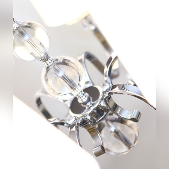 Détail des volutes chromées et des perles de verre de la suspension Charlotte