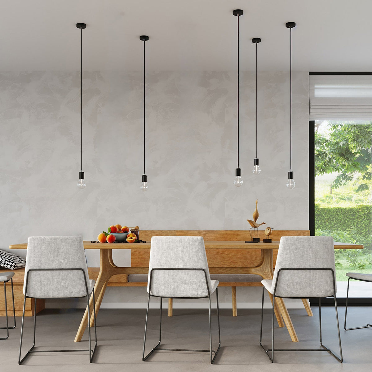 Cinq suspensions Edison noires à hauteurs variées au-dessus d'une table à manger en bois