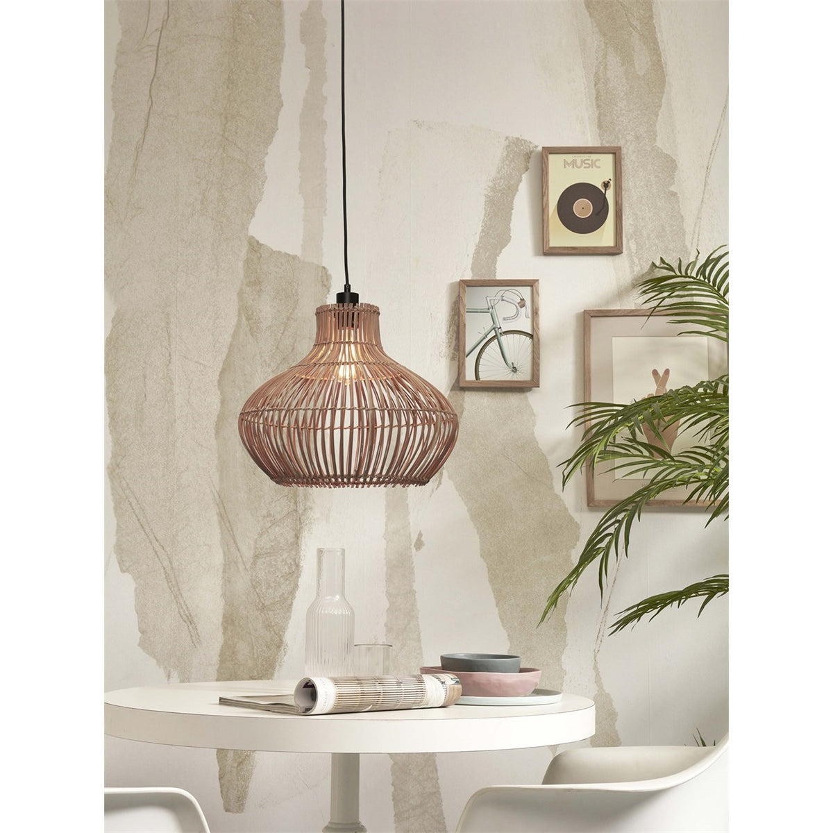 Suspension Kalahari en rotin allumée au-dessus d'une table ronde blanche près de cadres au mur