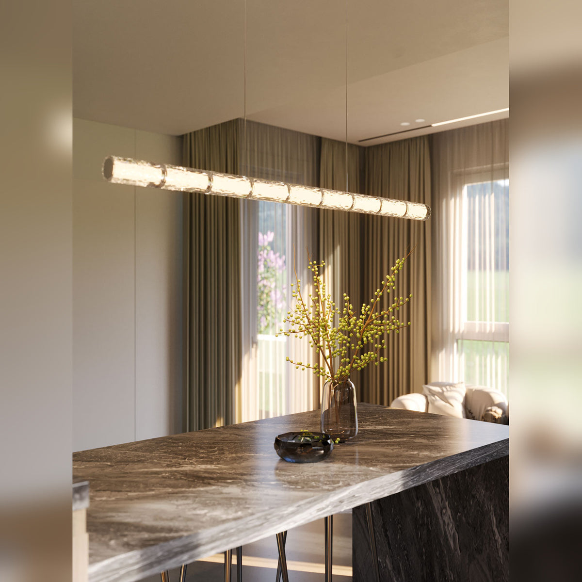 Suspension linéaire Love allumée au-dessus d'un îlot en marbre gris avec un vase de branches