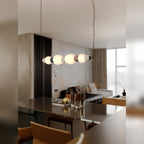 Suspension Modern allumée à l'horizontale au-dessus d'une table à manger au plateau sombre dans un séjour ouvert