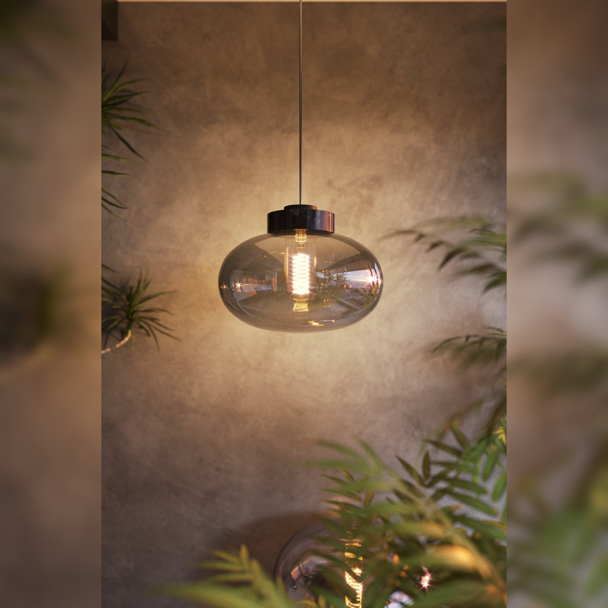 Suspension Moonstone verre fumé et marbre noir allumée devant un mur en béton entre des plantes