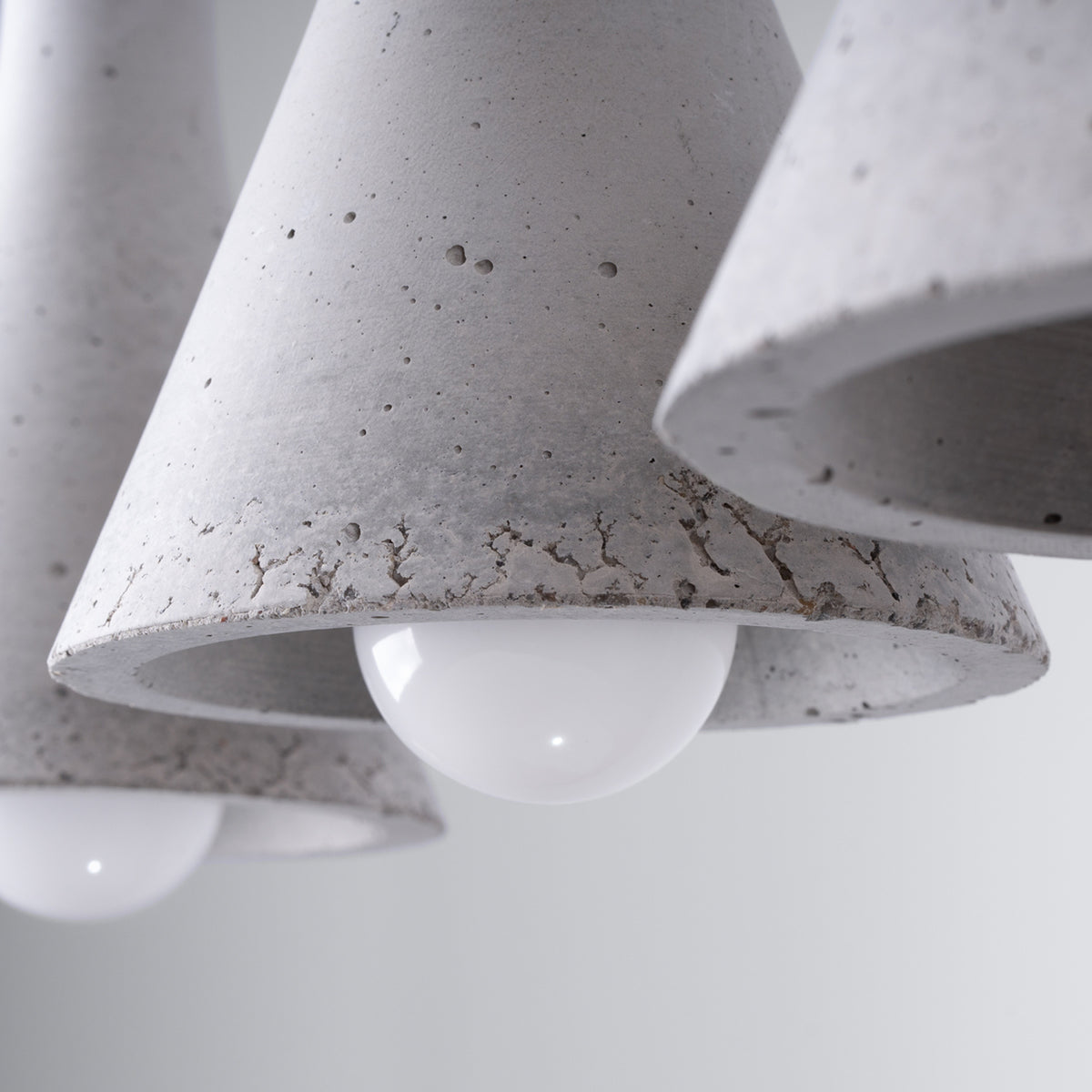 Détail du béton gris alvéolé des abat-jours Rea et de leurs ampoules opales