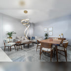 Suspension Ritz allumée dans un séjour contemporain entre un canapé clair et une table à manger en bois