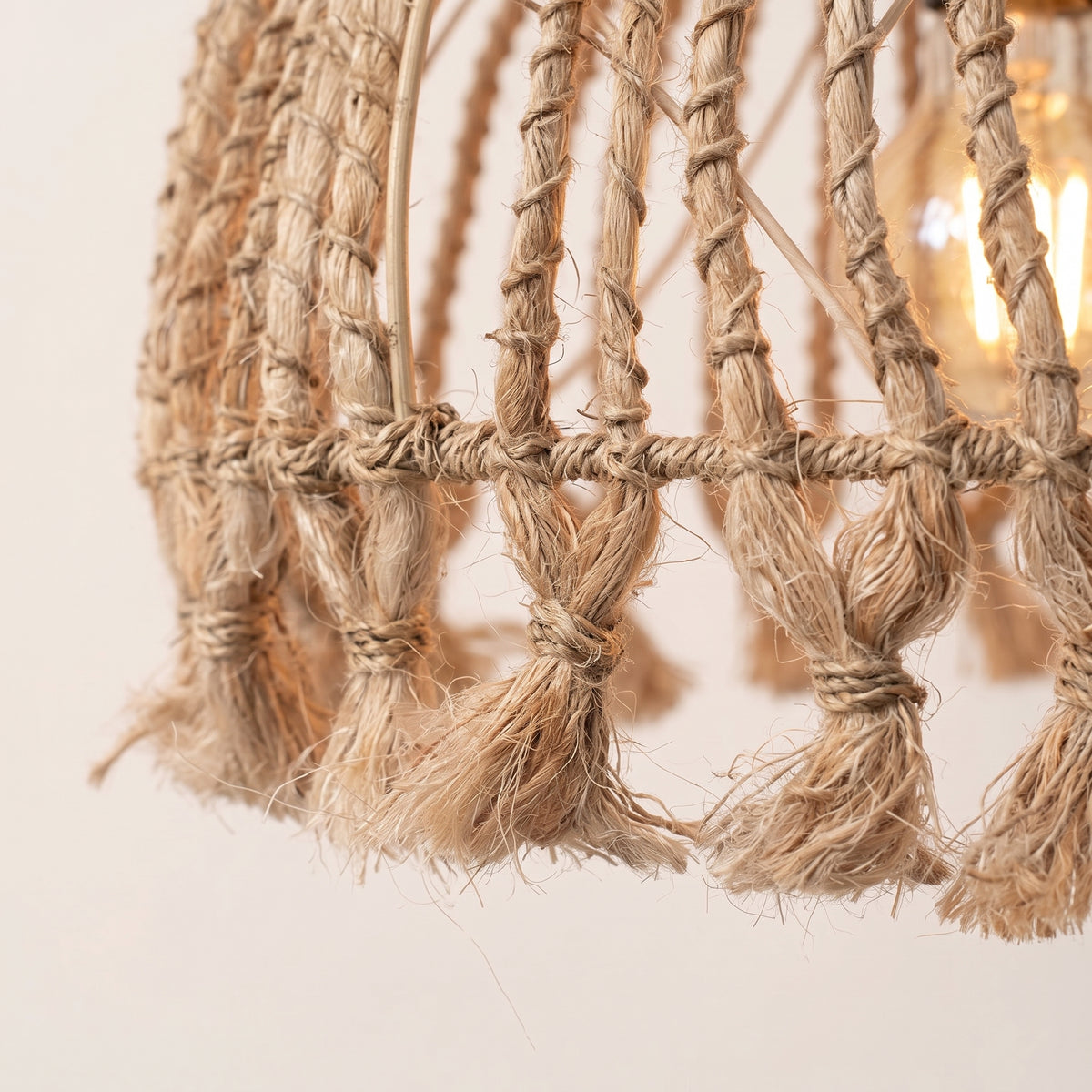 Gros plan sur les pompons noués en abaca naturel au bas de la suspension Tassel