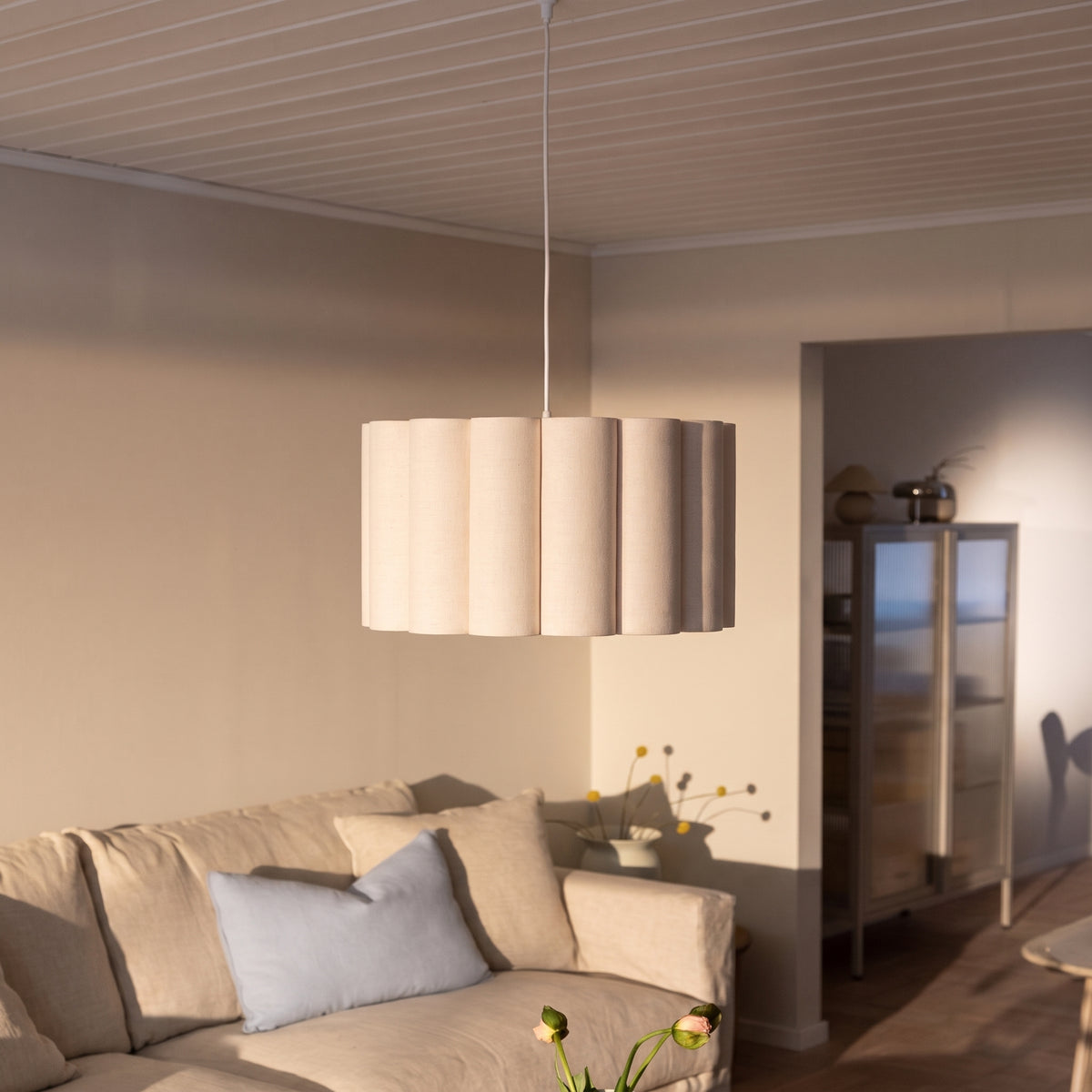 Suspension Watton au-dessus d'un canapé beige dans un salon, sous un plafond en lambris