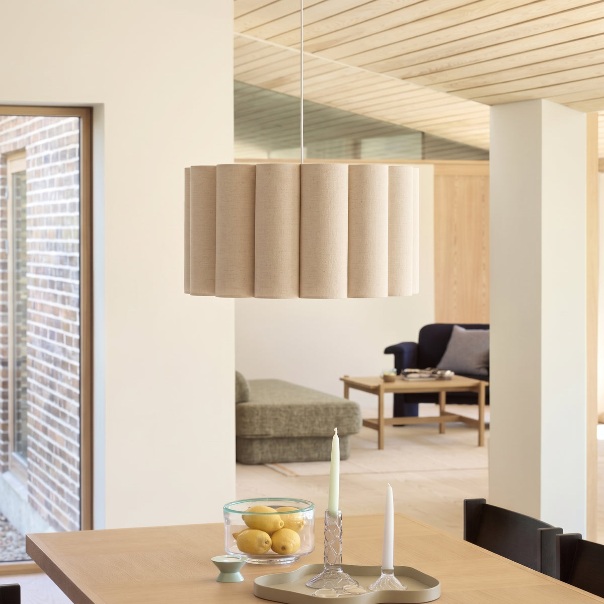 Suspension Watton au-dessus d'une table en bois clair dressée avec des citrons et des bougies