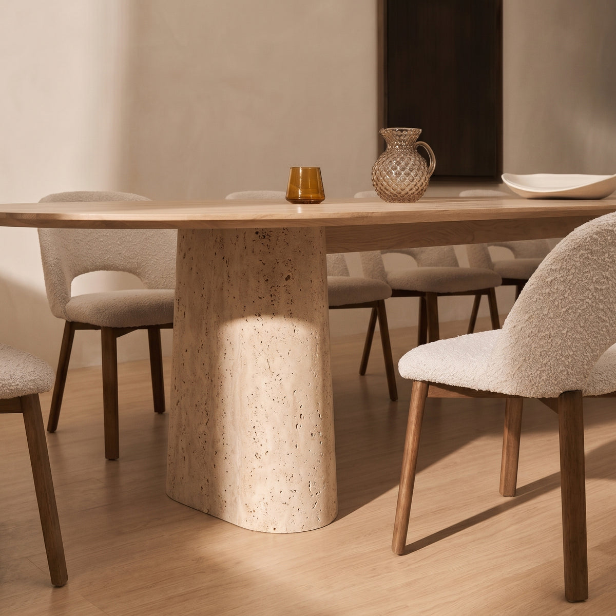 Socle en travertin de la table à manger Anchor 300 cm en chêne naturel, entouré de chaises à pieds en bois foncé et en bouclé blanc