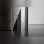 Détail du fût en acier noir facetté de la table Sharp à côté de la découpe en biais du lest en béton