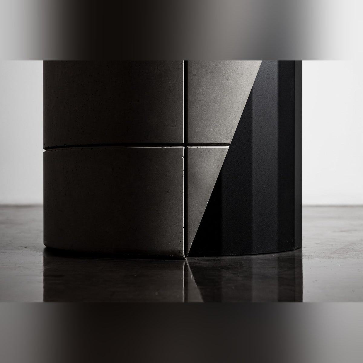 Détail du lest en béton de la table Sharp avec ses joints et sa découpe en biais contre le fût en acier noir