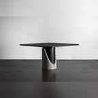 Table à manger Sharp carrée vue de trois quarts dans un studio au sol en béton sombre