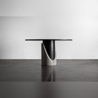 Table à manger Sharp ronde et la courbe de son lest en béton qui dévoile le fût en acier noir facetté