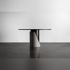 Table à manger Sharp ronde vue de profil avec la découpe en biais du lest en béton sur un sol sombre