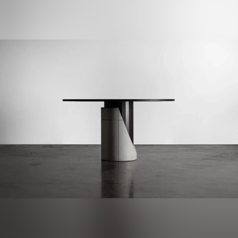 Table à manger Sharp ronde vue de profil avec la découpe en biais du lest en béton sur un sol sombre