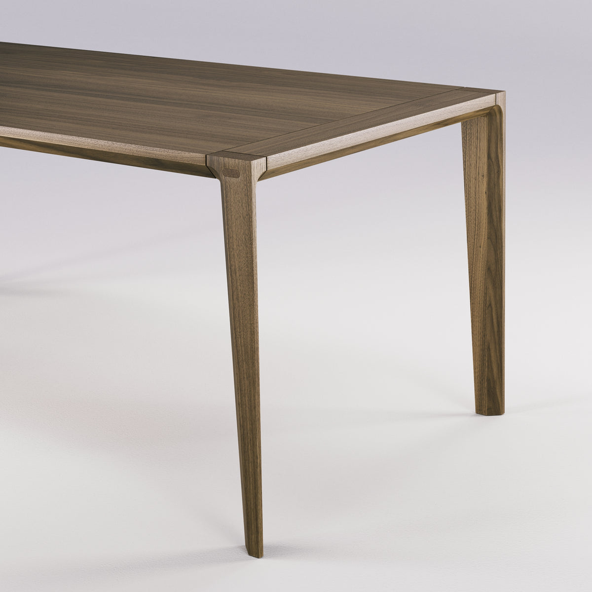 Angle du plateau et haut d'un pied de la table Raia en noyer foncé