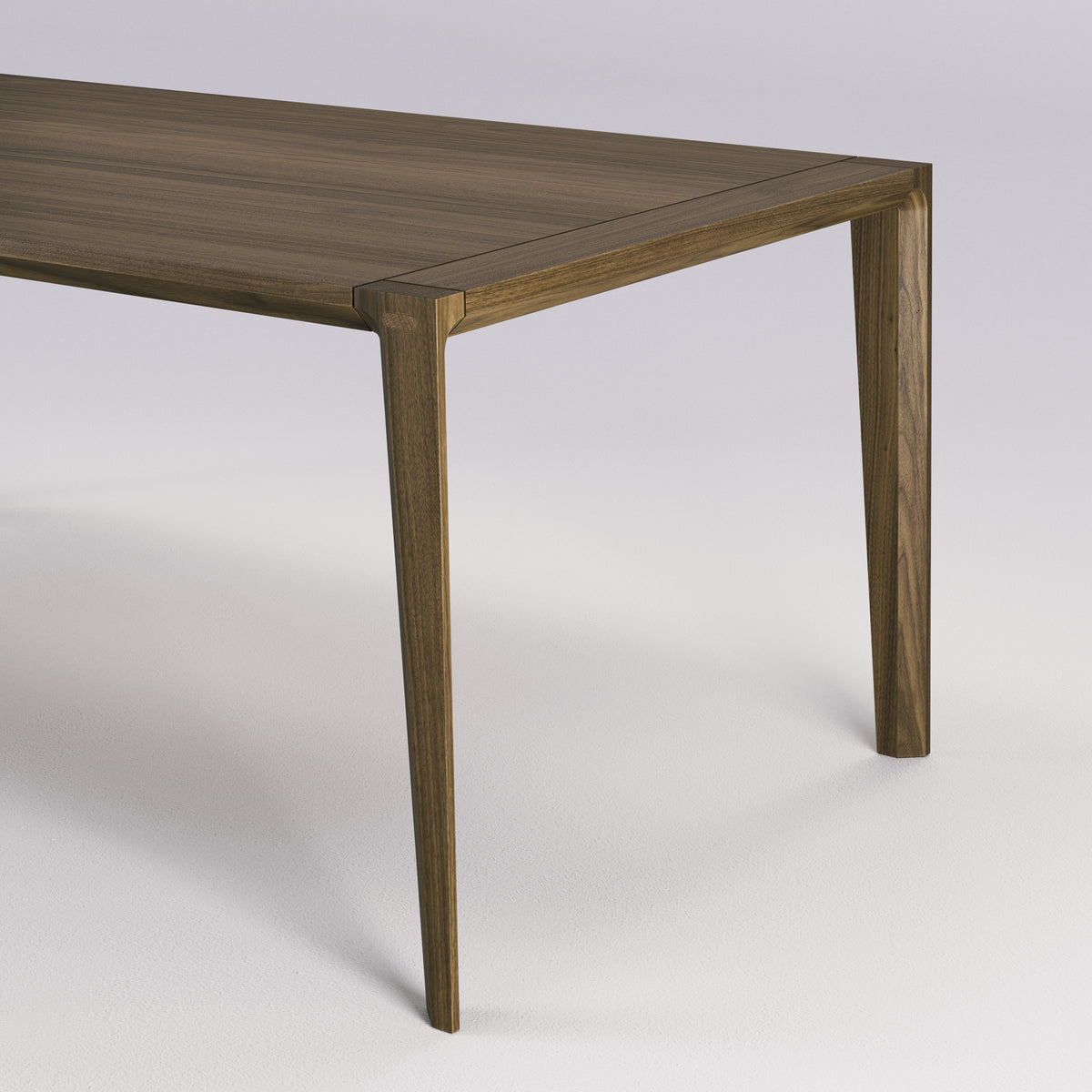 Angle du plateau et haut d'un pied de la table Raia en noyer foncé