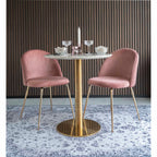 Table Bolzano dressée avec des coupes entre deux chaises en velours rose