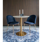 Table Bolzano dressée avec deux bougies entre deux chaises en velours bleu nuit