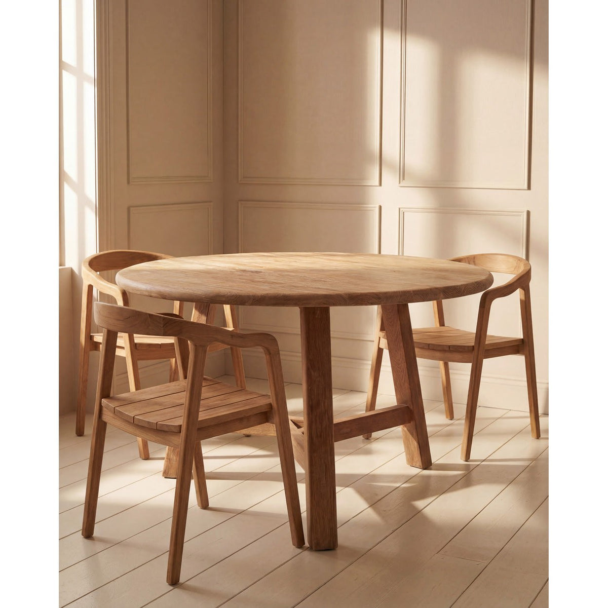 Table à manger ronde Noguchi en teck naturel entourée de trois fauteuils en teck dans une pièce aux murs moulurés