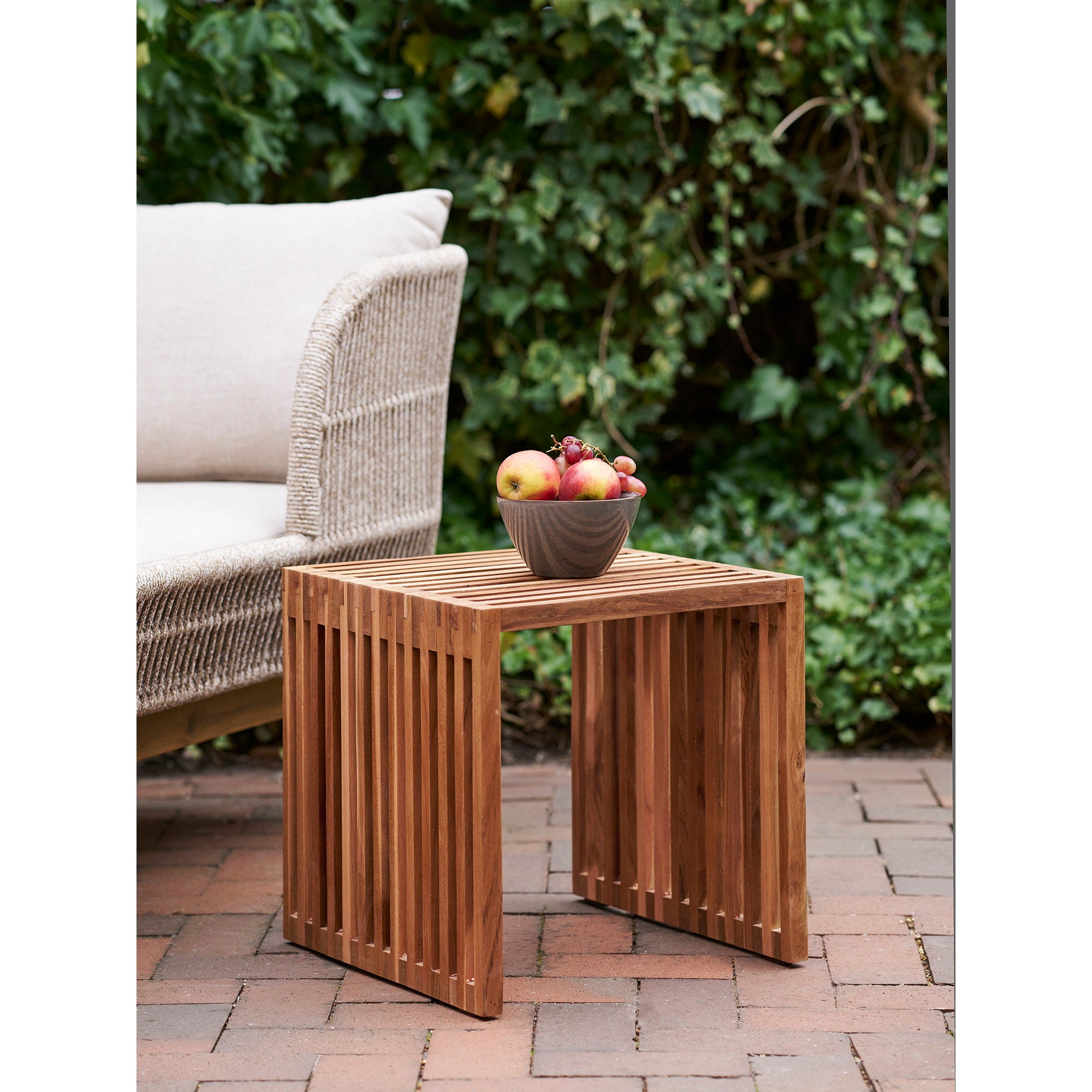 Table Pego teck naturel 40x40 cm aux côtés d'un salon de jardin corde écru