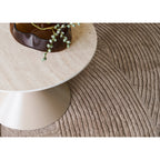 Plateau effet travertin de la table basse Annecy vu de dessus au-dessus d'un tapis beige à motif de vagues