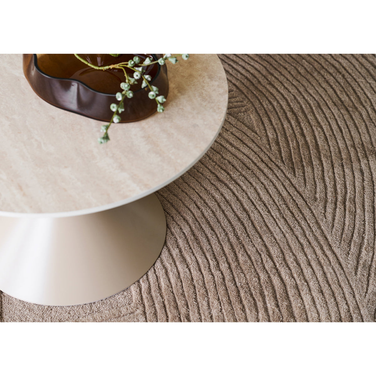 Plateau effet travertin de la table basse Annecy vu de dessus au-dessus d'un tapis beige à motif de vagues