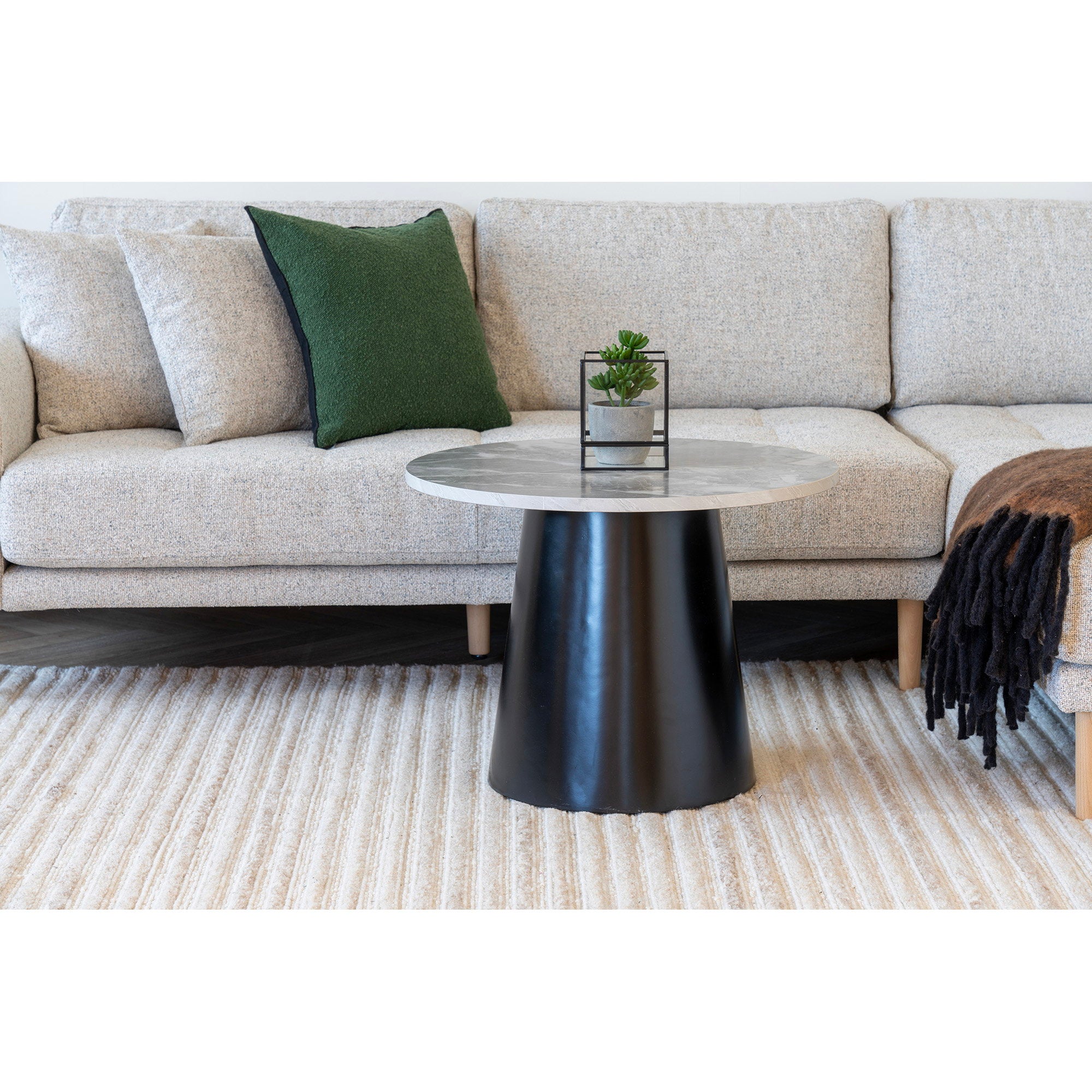 Table basse Brito marbre gris piédestal noir salon canapé d'angle beige tapis rayé