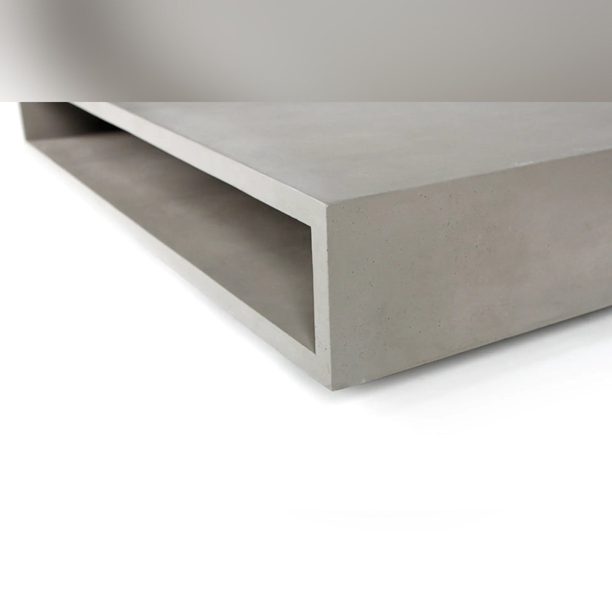 Gros plan sur un angle de la table basse Monobloc et sur l'épaisseur du béton autour de la niche