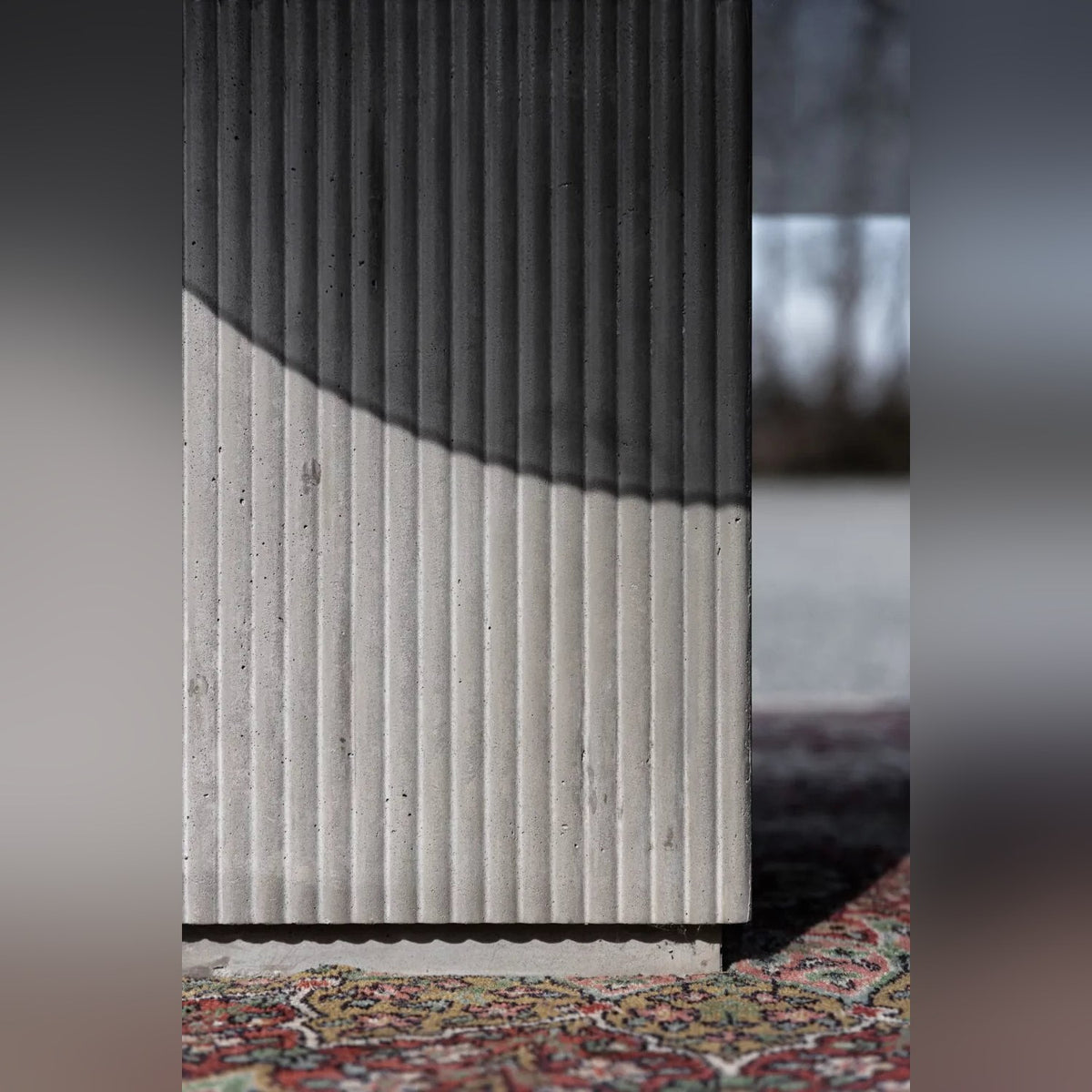 Cannelures du piètement en béton gris naturel de la table basse Strut carrée sous une lumière rasante