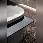 Détail du capot en béton aux bords cannelés posé sur le plateau en verre teinté de la table basse Strut carrée