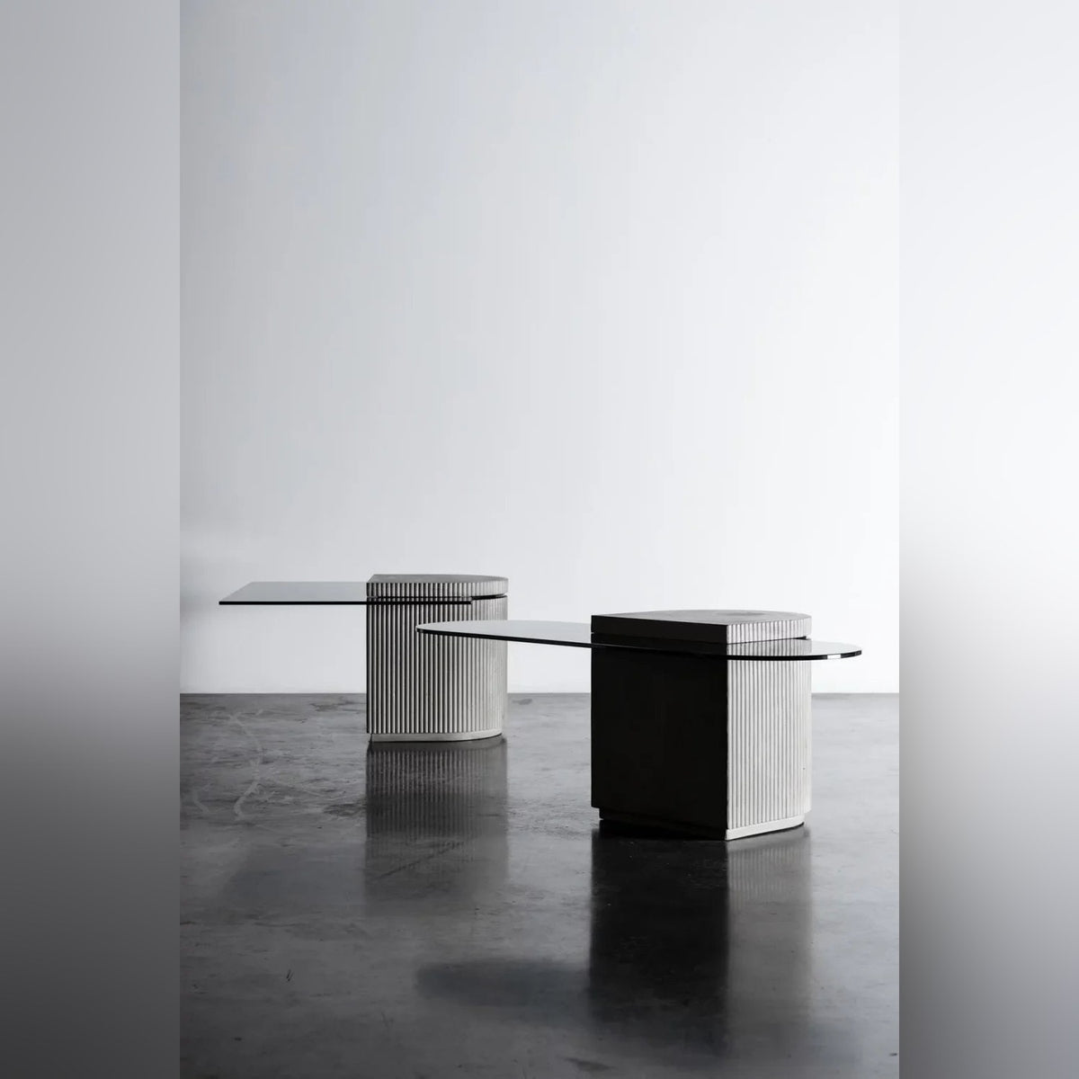 Table basse Strut oblongue au premier plan et une table Strut à plateau rectangulaire au fond dans un studio au sol sombre