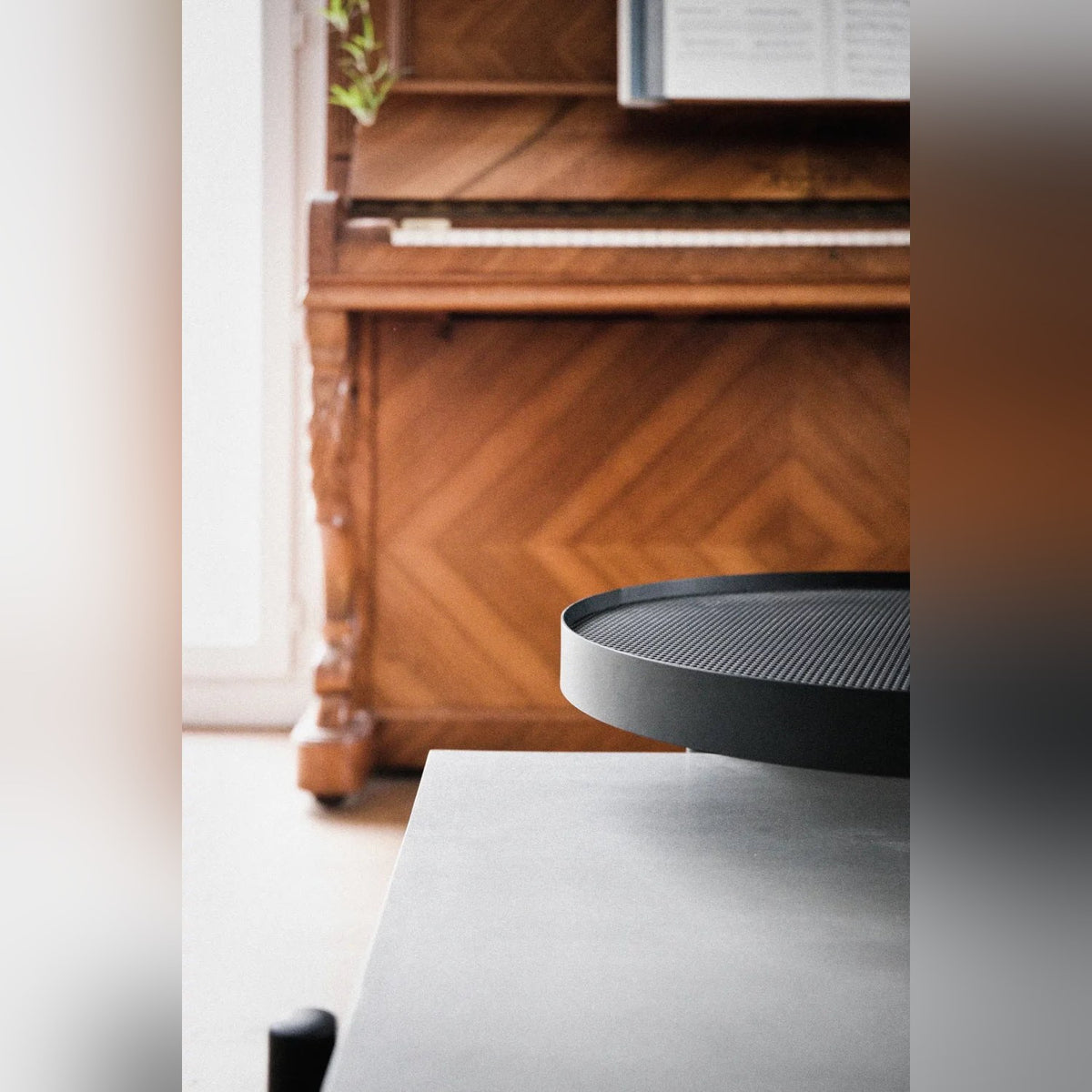 Bord du plateau pivotant noir au-dessus du béton gris avec un piano en bois en arrière-plan