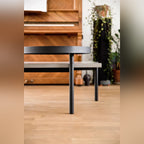 Table basse Twist en béton devant un piano en bois et des plantes avec le plateau pivotant sur son axe