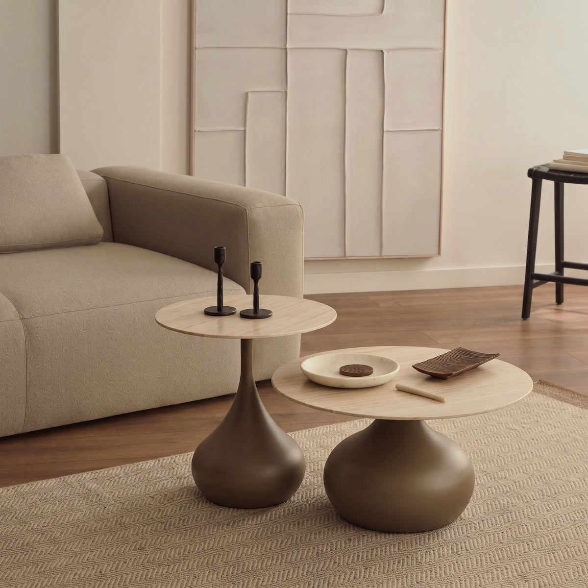 Lot de 2 tables basses Pienza devant un canapé beige, avec deux bougeoirs noirs sur la petite et une coupelle sur la grande