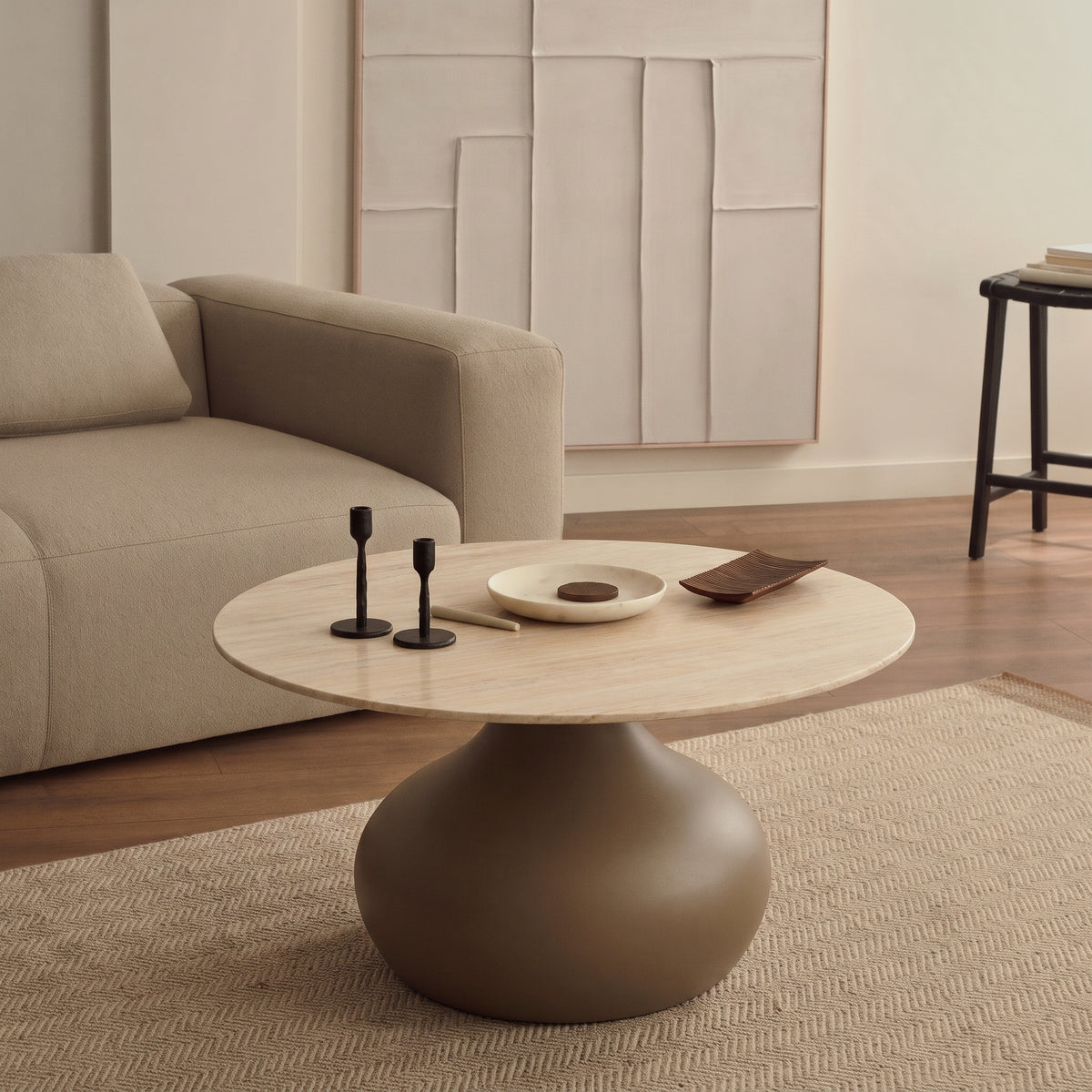 Table basse Pienza devant un canapé beige, sur un tapis à chevrons, avec bougeoirs noirs et coupelle sur le plateau