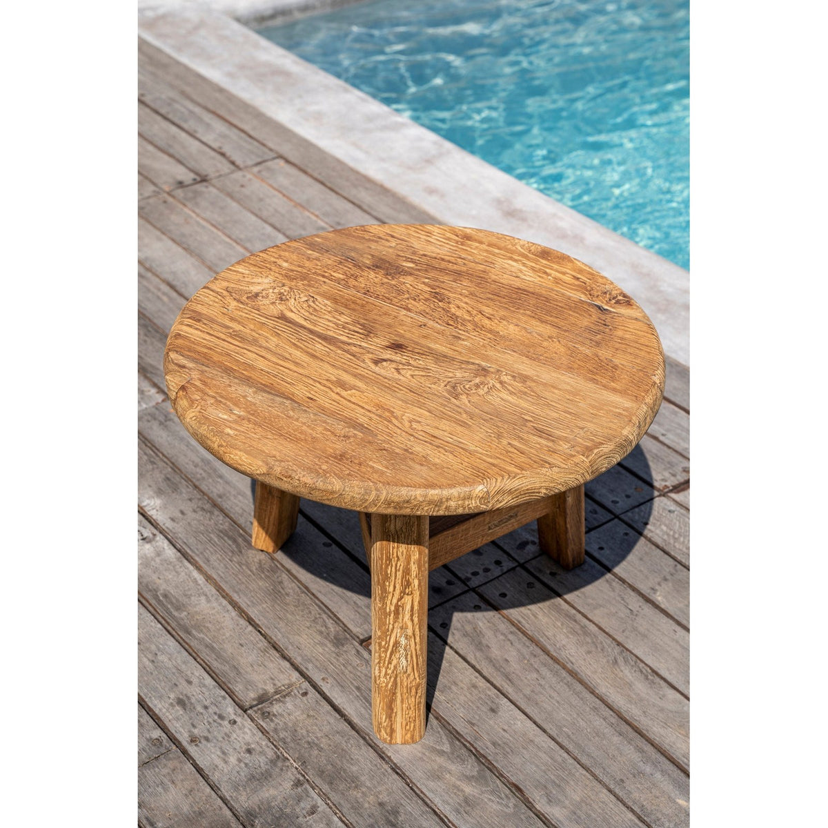 Table basse Fusuma en teck photographiée sur une terrasse en bois au bord d'une piscine