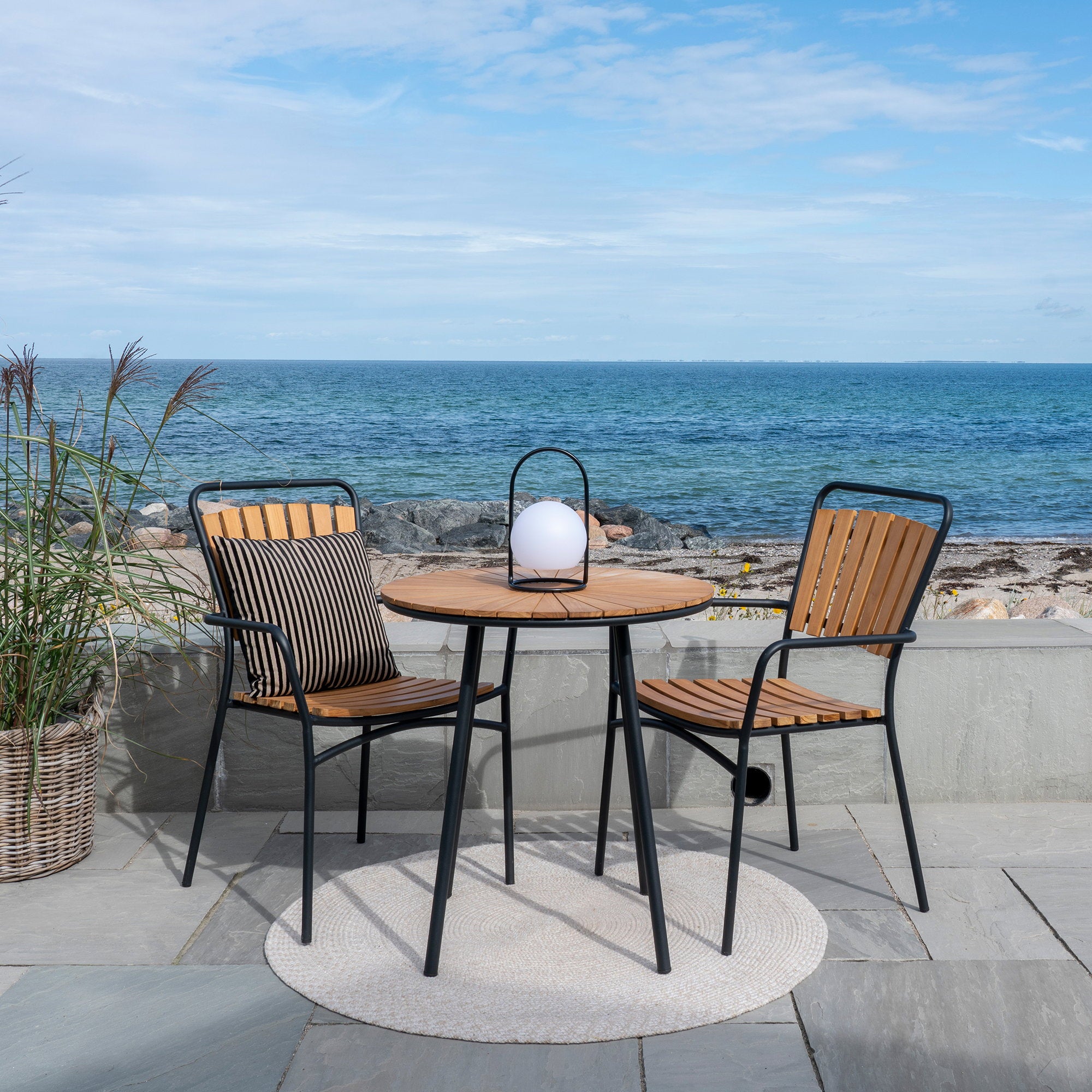 Table bistro Cleveland teck noir terrasse bord de mer avec chaises et coussin rayé
