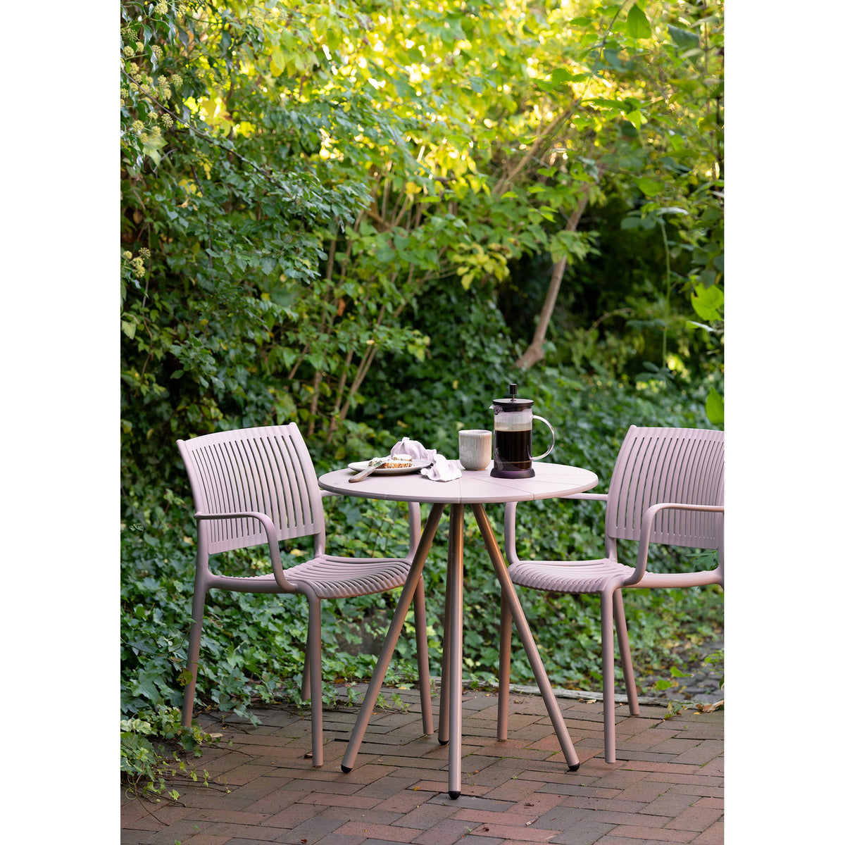 Table Barletta entre deux fauteuils de jardin à accoudoirs sur une terrasse en briques