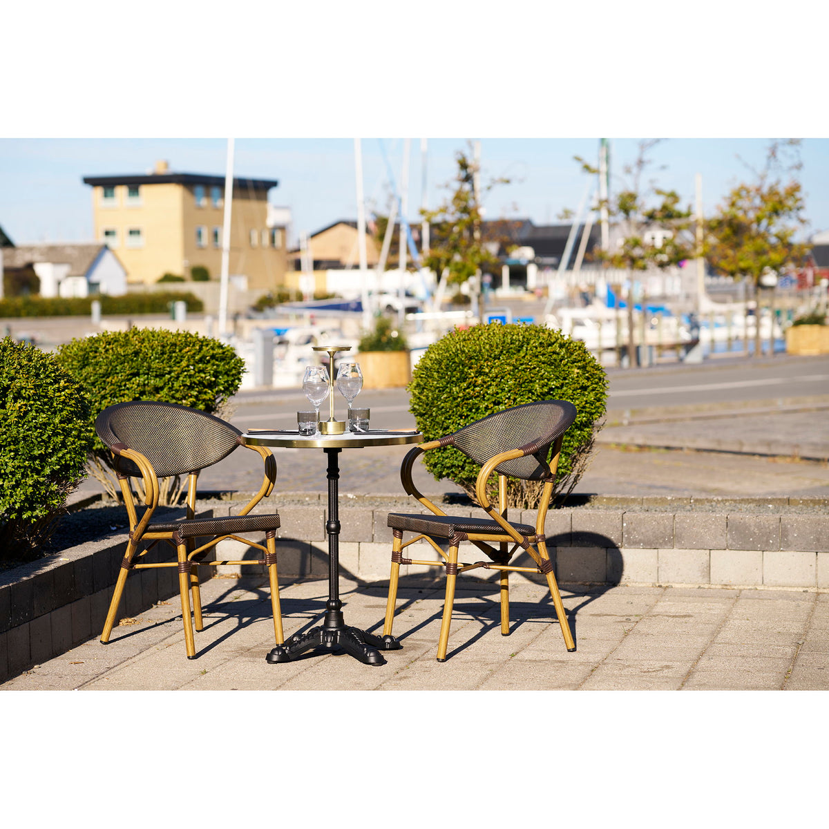 Table bistrot et deux chaises de bistrot sur une terrasse face aux bateaux