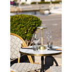 Table bistrot dressée de verres et d'une lampe dorée sur une terrasse ensoleillée