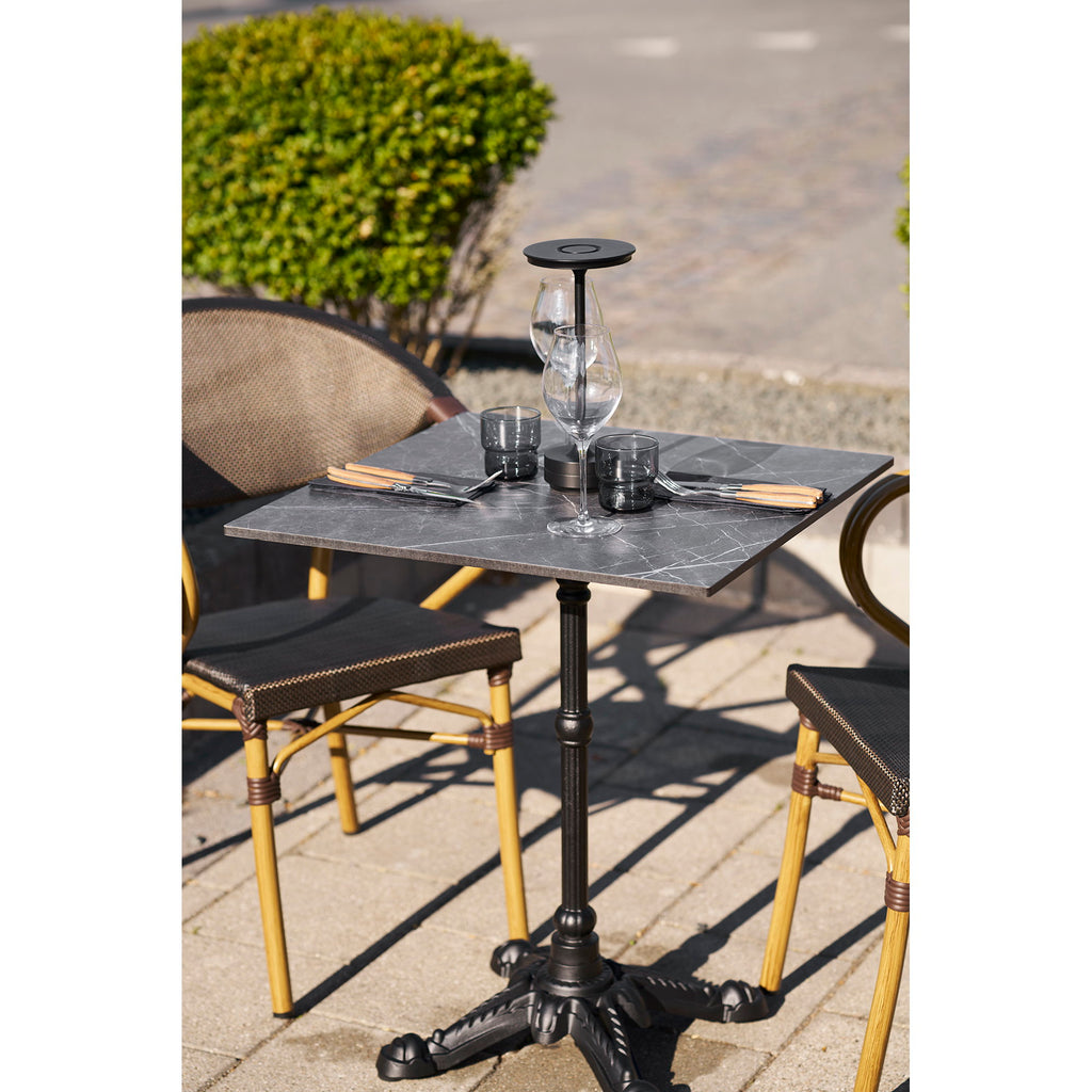 Table bistrot carrée marbre noir dressée verres à vin terrasse extérieure style parisien