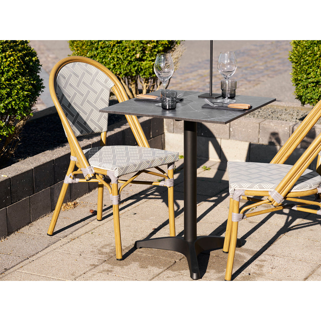 Table bistrot effet marbre noir dressée terrasse ensoleillée chaises bistrot grises port