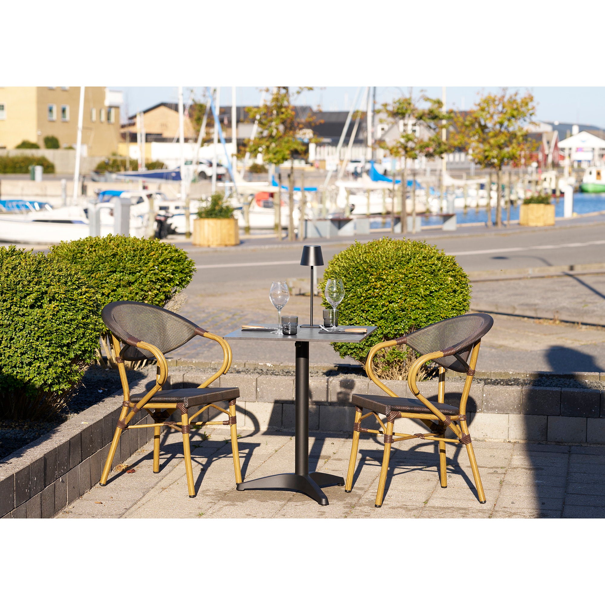 Table bistrot marbre noir aluminium en situation terrasse bord de mer chaises bistrot rotin